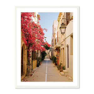 Framed photography print of a narrow sunlit street in Crete lined with old stone buildings and vibrant pink bougainvillea blooming along the wall titled Pink Bougainvillea, Crete.